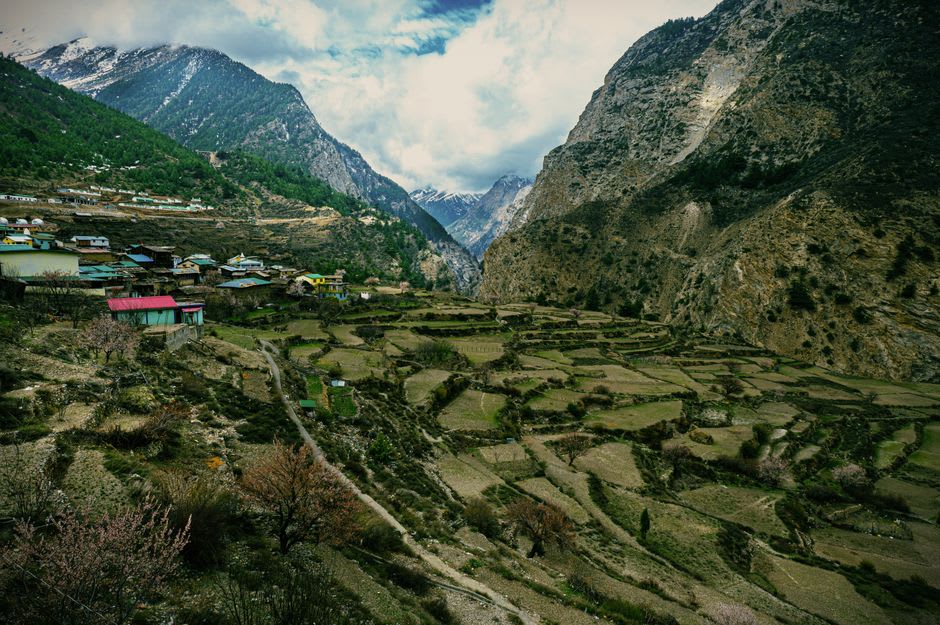 Terraced hillside farmland along the trail approaching Tarkeghyang with distant Himalayan peaks catching afternoon light