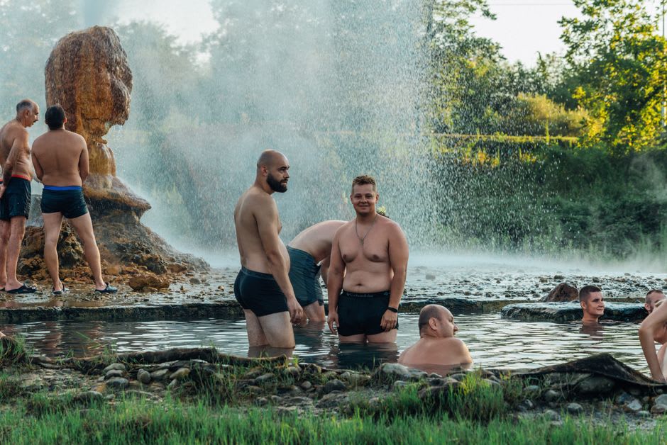 Randonneurs se prélassant dans les bassins de pierre des sources chaudes de Tatopani, avec la vallée de la rivière visible au loin