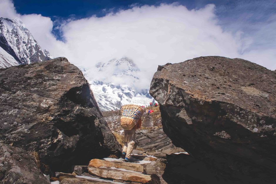 Des randonneurs traversant l'exposée section d'éboulis de la zone d'éboulement en route vers le camp de base de Tilicho