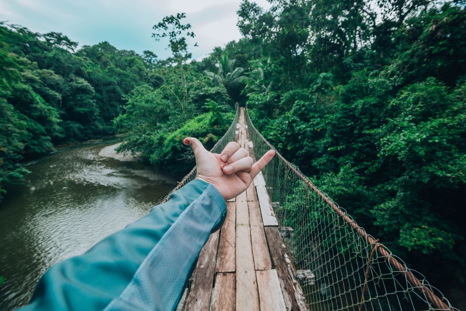 El antiguo puente colgante colonial sobre el río en La Foa, con palmeras bordeando la orilla cercana