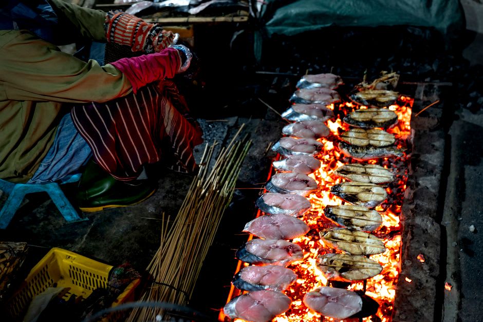 A roadside stall near Poindimié selling grilled fish and coconut crab with the lagoon and reef visible behind