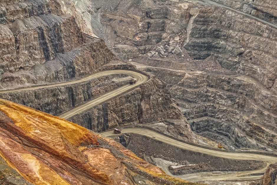 A red-earth open-pit nickel mine cut into a green mountainside near Thio, haul roads visible switchbacking up the slope