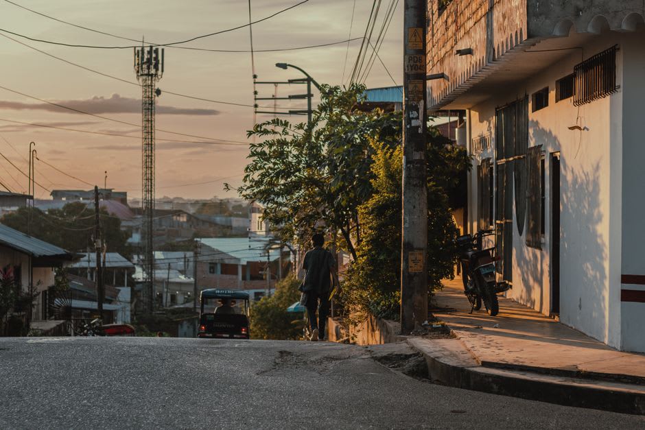 A quiet street in the town of Voh with the surrounding mangrove flats and low hills visible beyond the rooftops