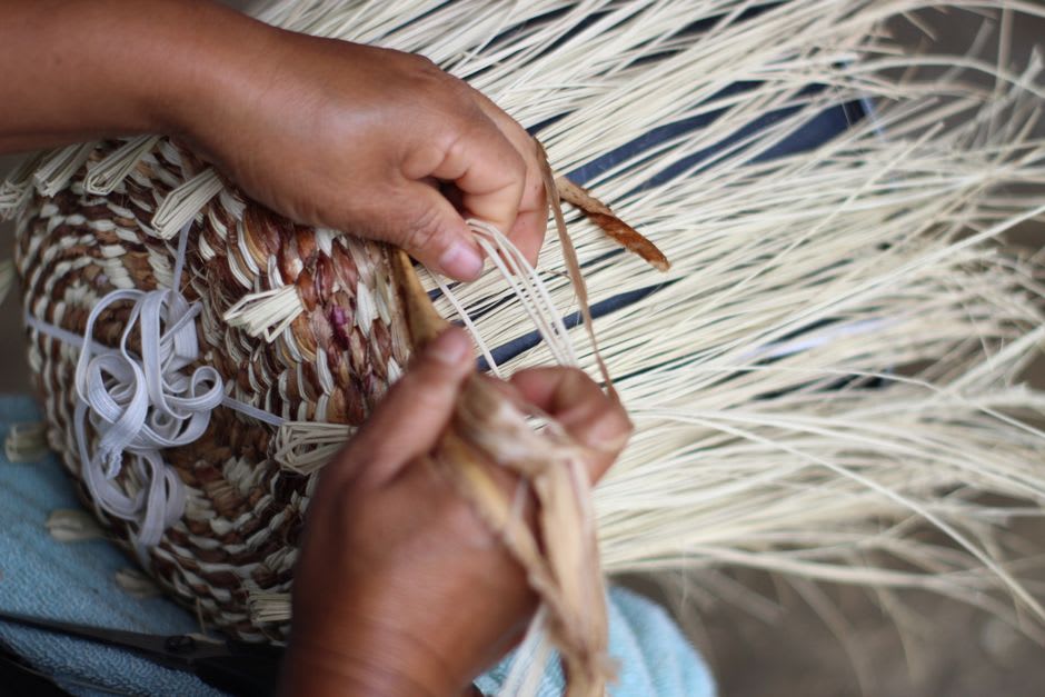 A weaver's hands working palm fiber into the brim of a traditional hat in Camoapa