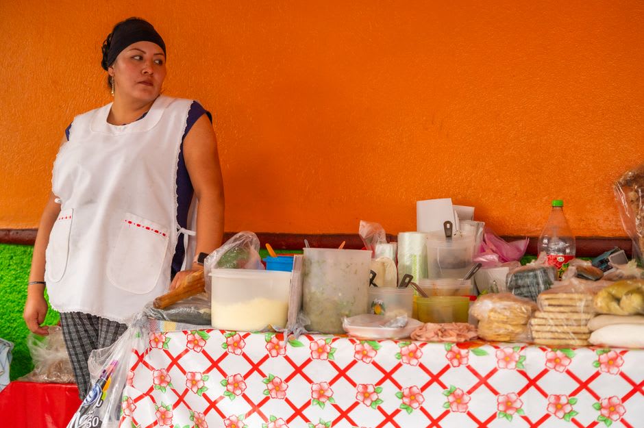 A vendor preparing quesillo wrapped in a warm tortilla at a roadside stall
