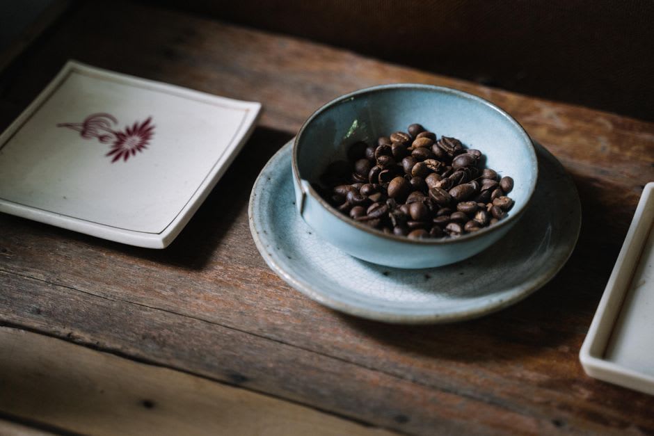 A wooden cupping table with rows of small bowls of brewed coffee, Lake Nicaragua and its islands visible in the distance below