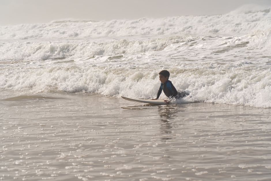 Surfista principiante atrapando una ola pequeña en la espuma en Playa Maderas