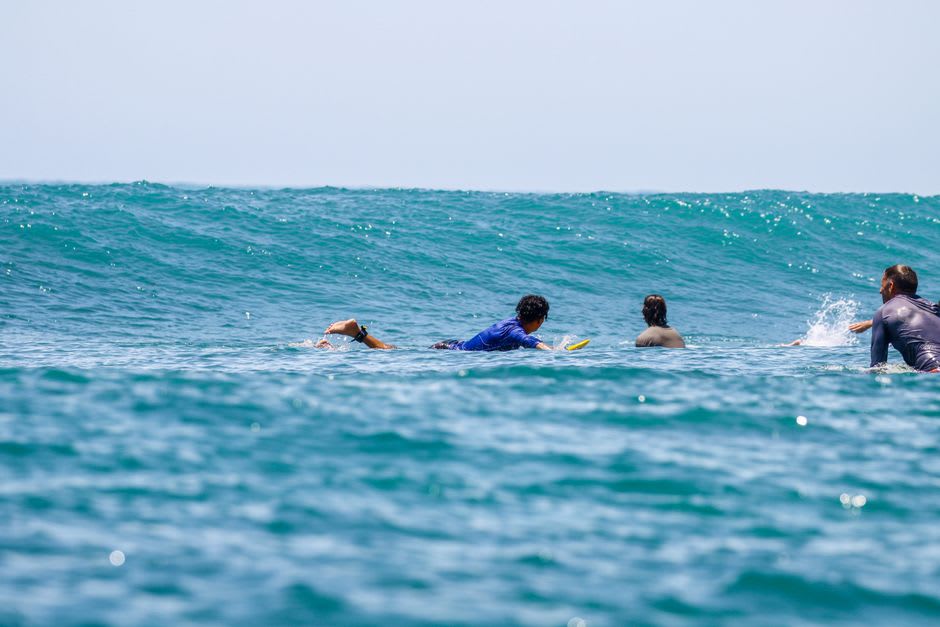 Wave breaking over the reef at Popoyo with a lone surfer paddling out