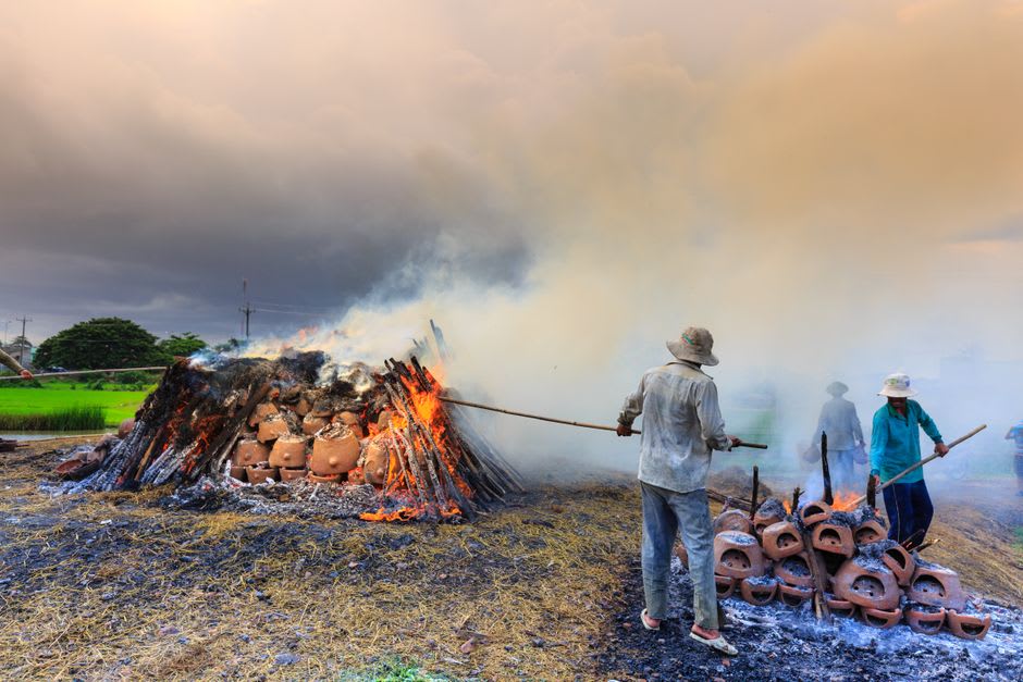 Ceramic pieces being fired in a traditional wood-burning kiln at dusk
