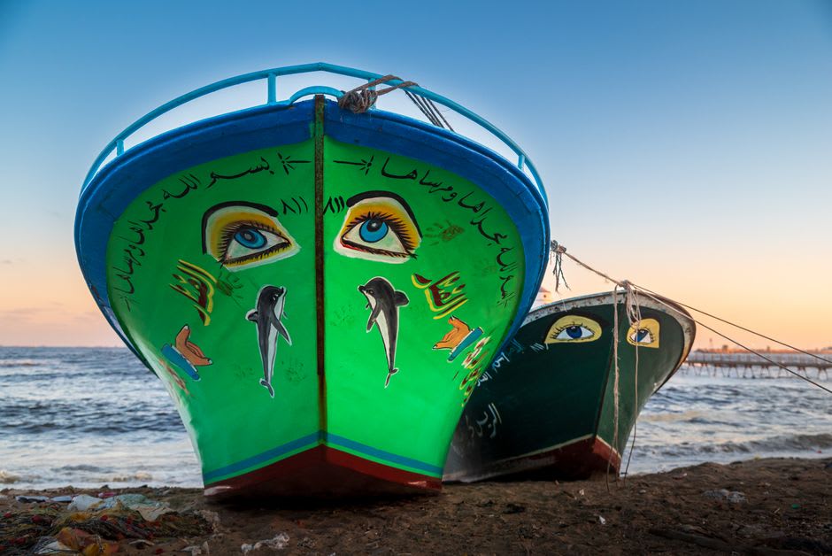 A primitivist painting of lake birds and boats drying outside an artist's home in Solentiname