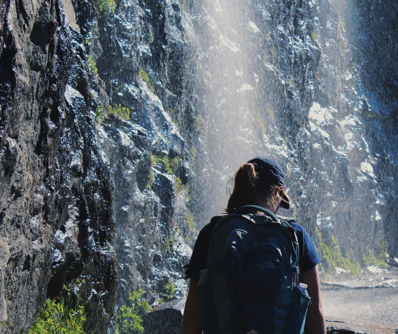Hikers climbing wet rock steps beside the cascading tiers of Erin Ijesha Waterfalls
