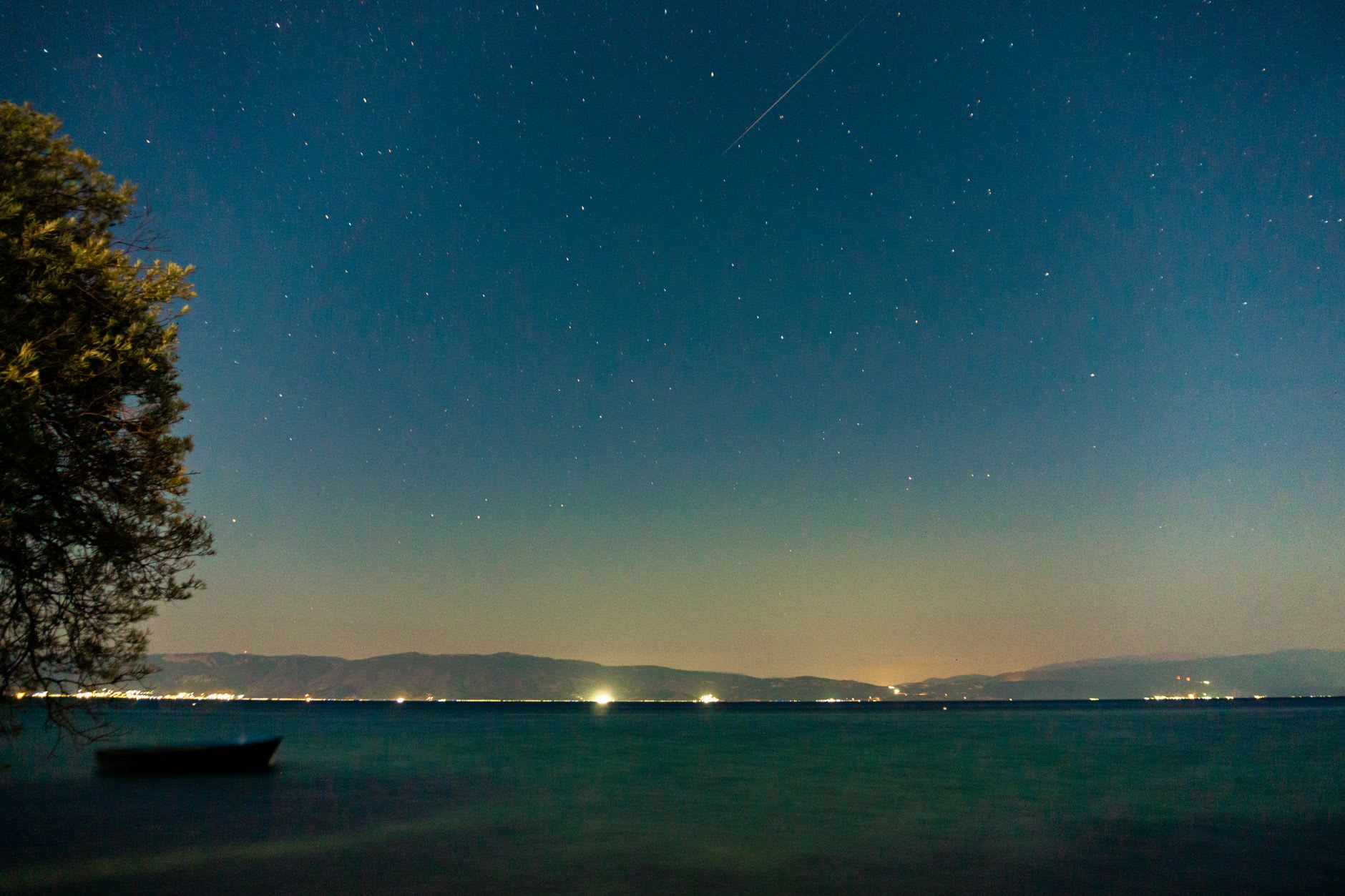 Le tranquille village de pêcheurs de Stenje sur la rive macédonienne du lac Prespa, des barques en bois tirées sur une plage étroite, les montagnes albanaises derrière