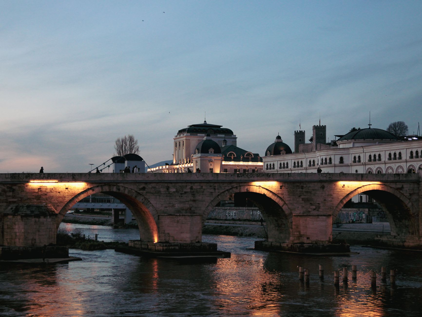 The Stone Bridge over the Vardar River at dusk, connecting the new city to the Ottoman Old Bazaar beyond