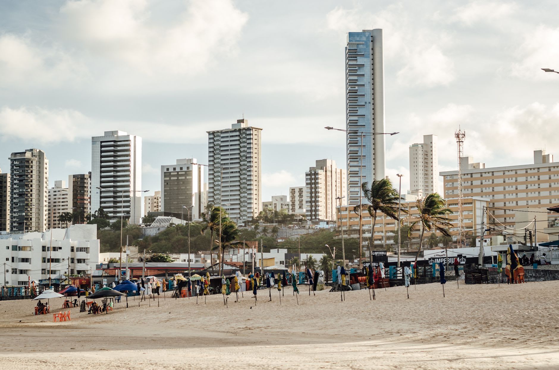 Una vista panorámica desde una duna de Genipabu mirando hacia el sur sobre el estuario del río Potengi y la ciudad distante de Natal, la arena al frente naranja en la luz de la tarde, el río plateado abajo