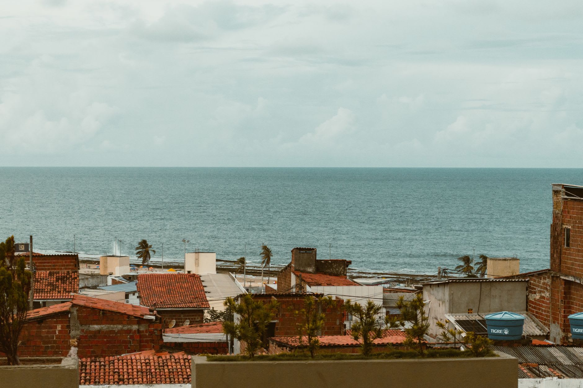Dentro del Forte dos Reis Magos en Natal — gruesos muros de fort colonial con troneras abiertas al Atlántico azul brillante, una bandera moviéndose en el viento alisio arriba