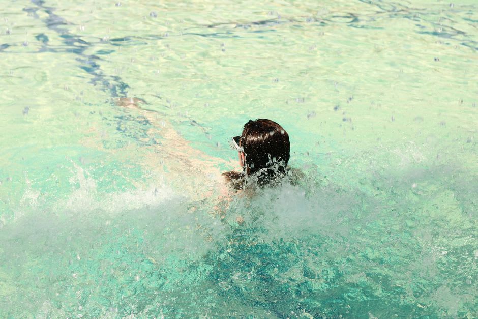 Bañistas flotando en el agua turquesa cristalina de las termas de Mataranka rodeados de altas palmeras