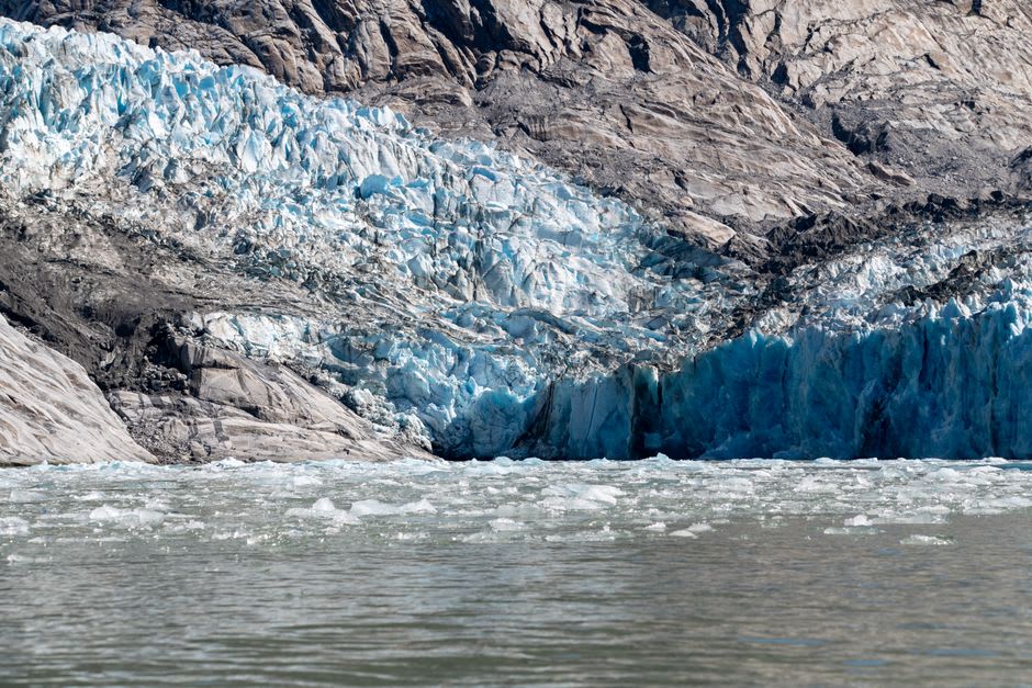 Meltwater streaming off the blue ice tongue of Briksdalsbreen glacier into a rocky valley
