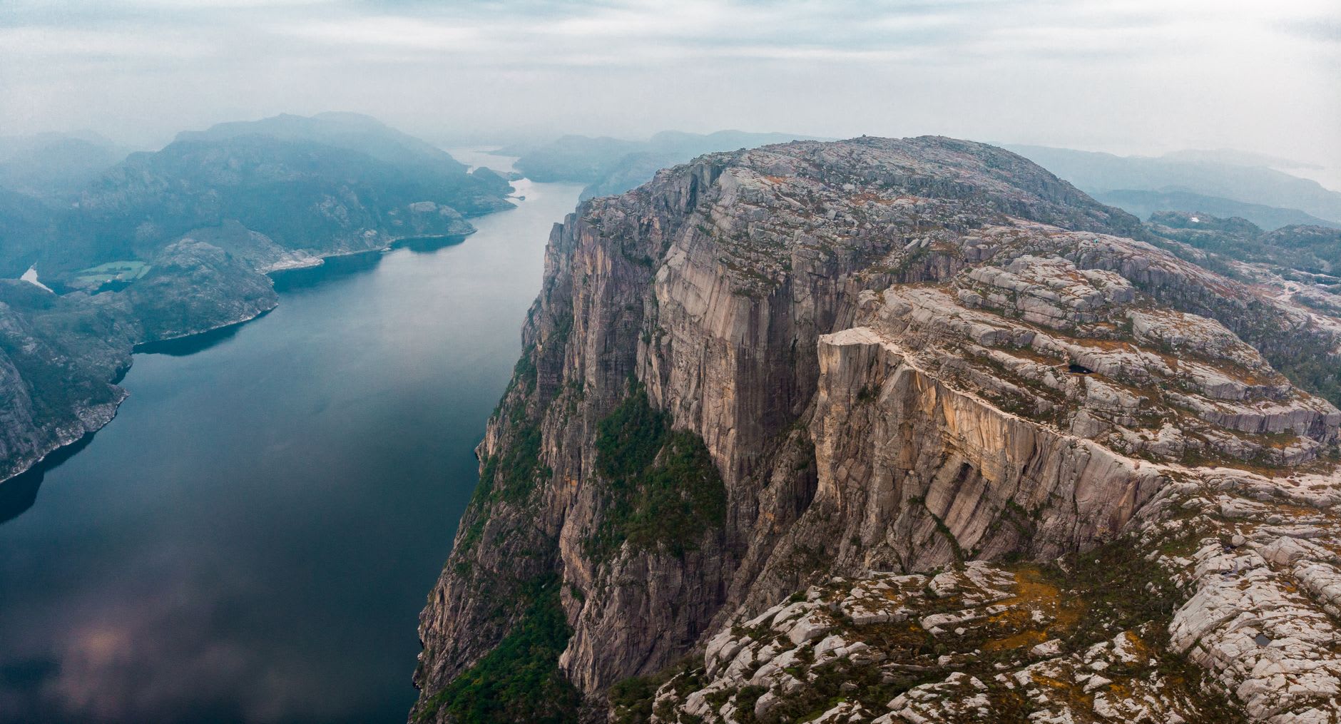 The chain-assisted ascent over wet bare granite on the trail to Kjerag, with hikers hauling themselves up the steep rock