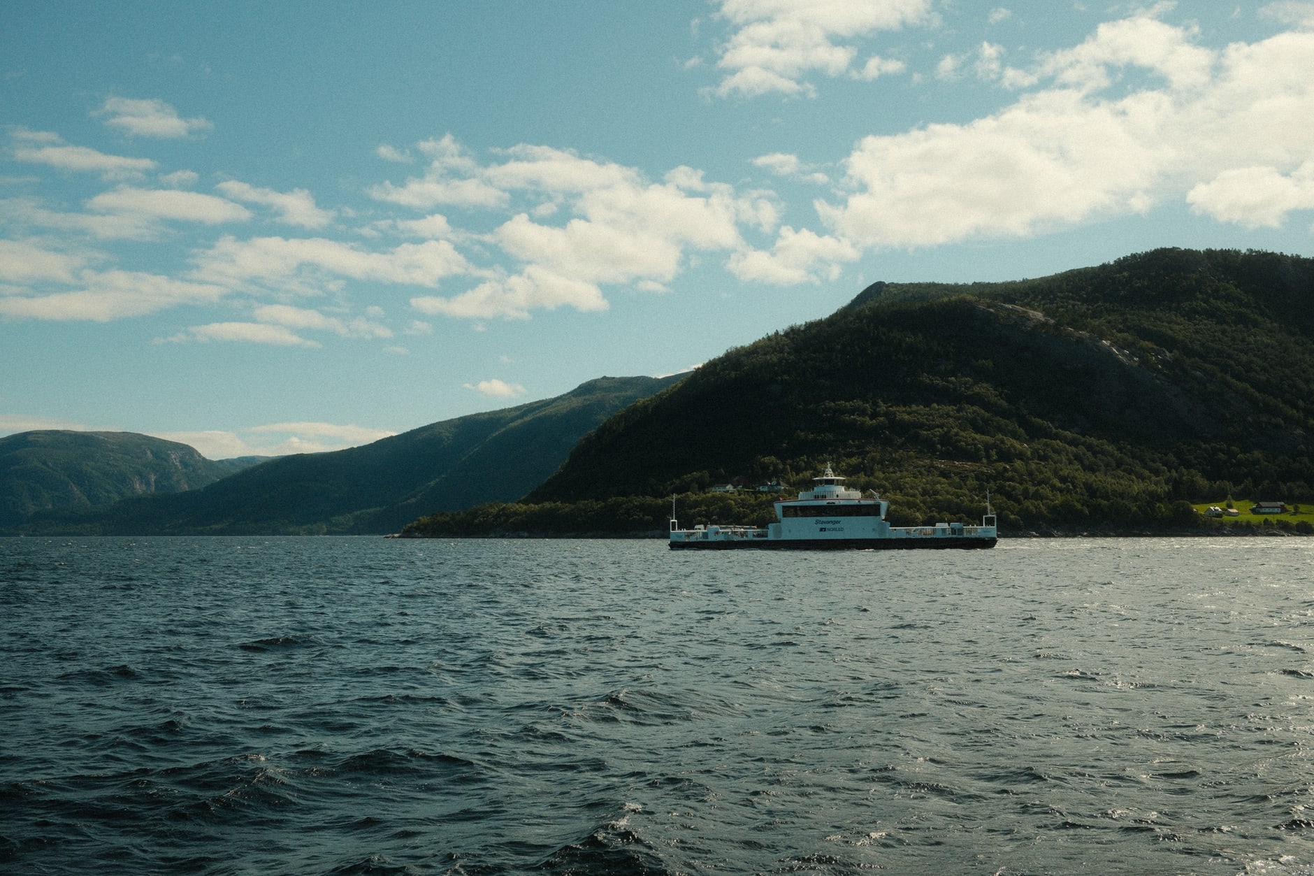 Turquoise glacial water in the Lustrafjord arm at Sognefjord, distinct color change where glacier melt meets the darker fjord, mountain reflected in the foreground