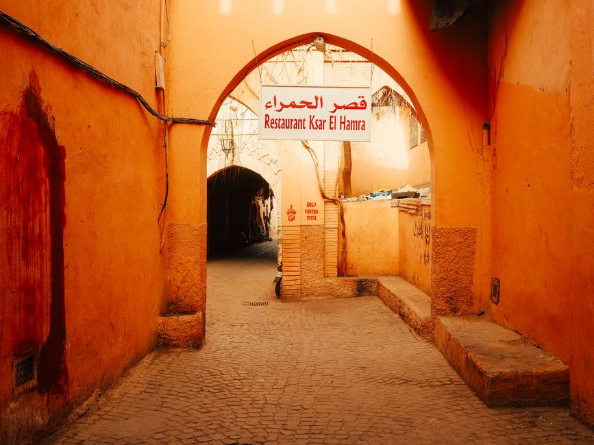 Los estrechos callejones de adobe del barrio antiguo de Al Hamra, casas vacías a ambos lados bajo un cielo despejado