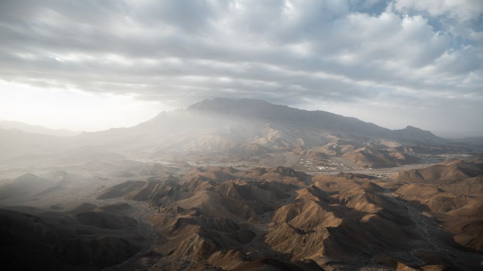 Empty coastal road running along Masirah Island's flat, arid landscape toward the sea