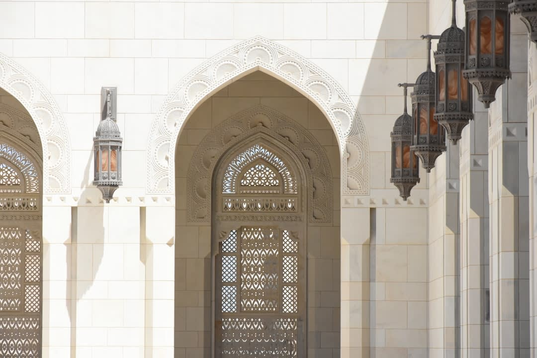 Interior del auditorio del Royal Opera House Muscat con balcones de madera tallada y candelabro