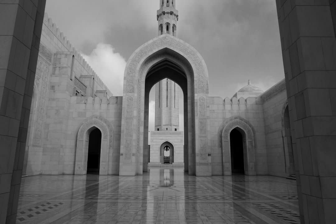Plaza ajardinada y fuentes fuera del Royal Opera House Muscat al anochecer