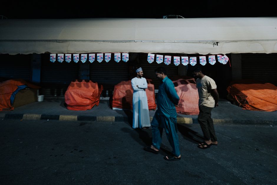 Bedouin traders negotiating over penned goats at the Sinaw livestock market, Oman