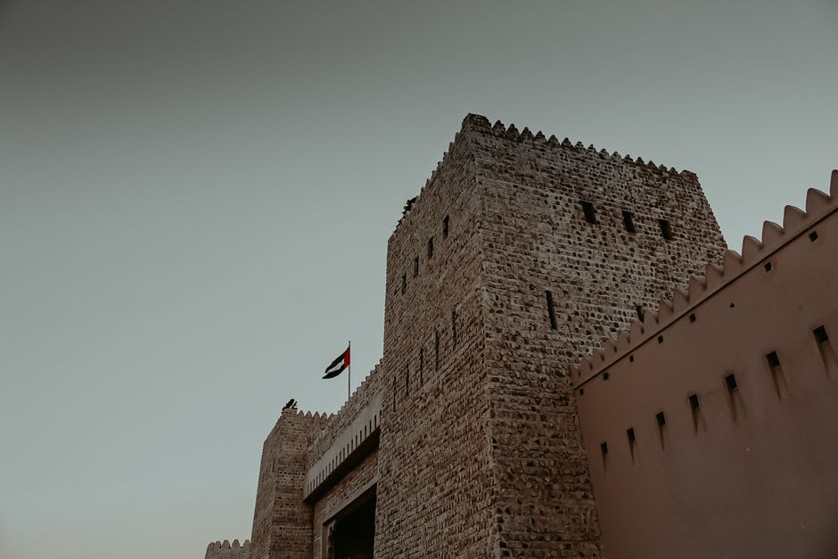 Sohar Fort's main tower viewed from the courtyard below, with old cannons positioned along the wall