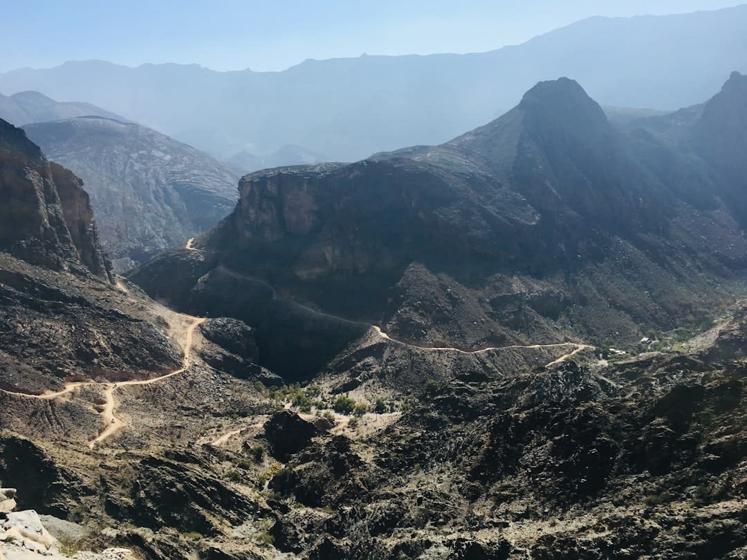 Ruined stone houses of an abandoned village built into a bend of Wadi Mayh's canyon, Oman
