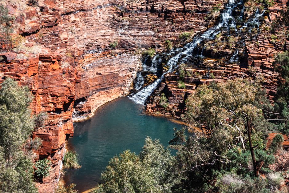 Circular Pool at Karijini at dusk, still turquoise water ringed by dark folded rock walls