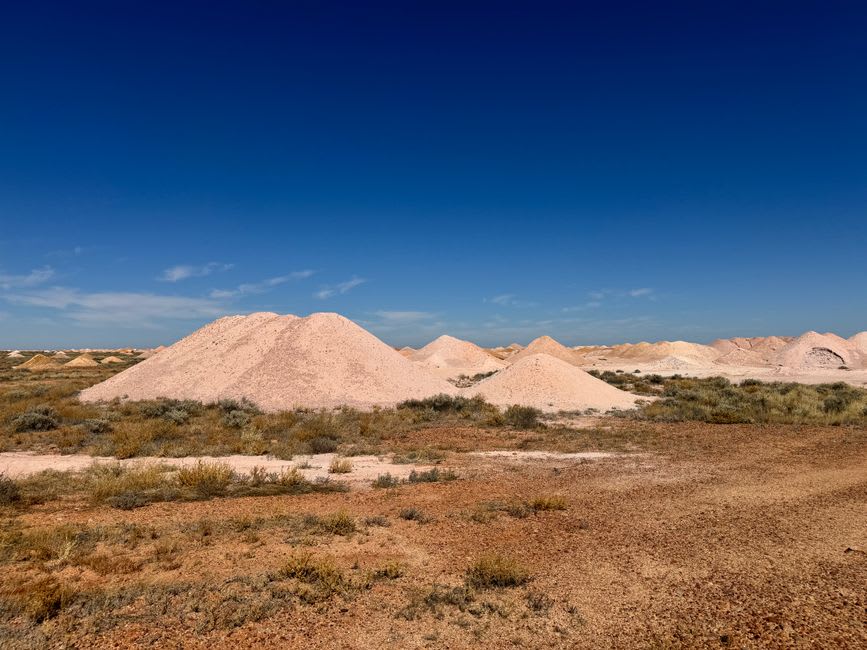 Pale mullock heaps of excavated earth scattered across the red dirt landscape around Lightning Ridge