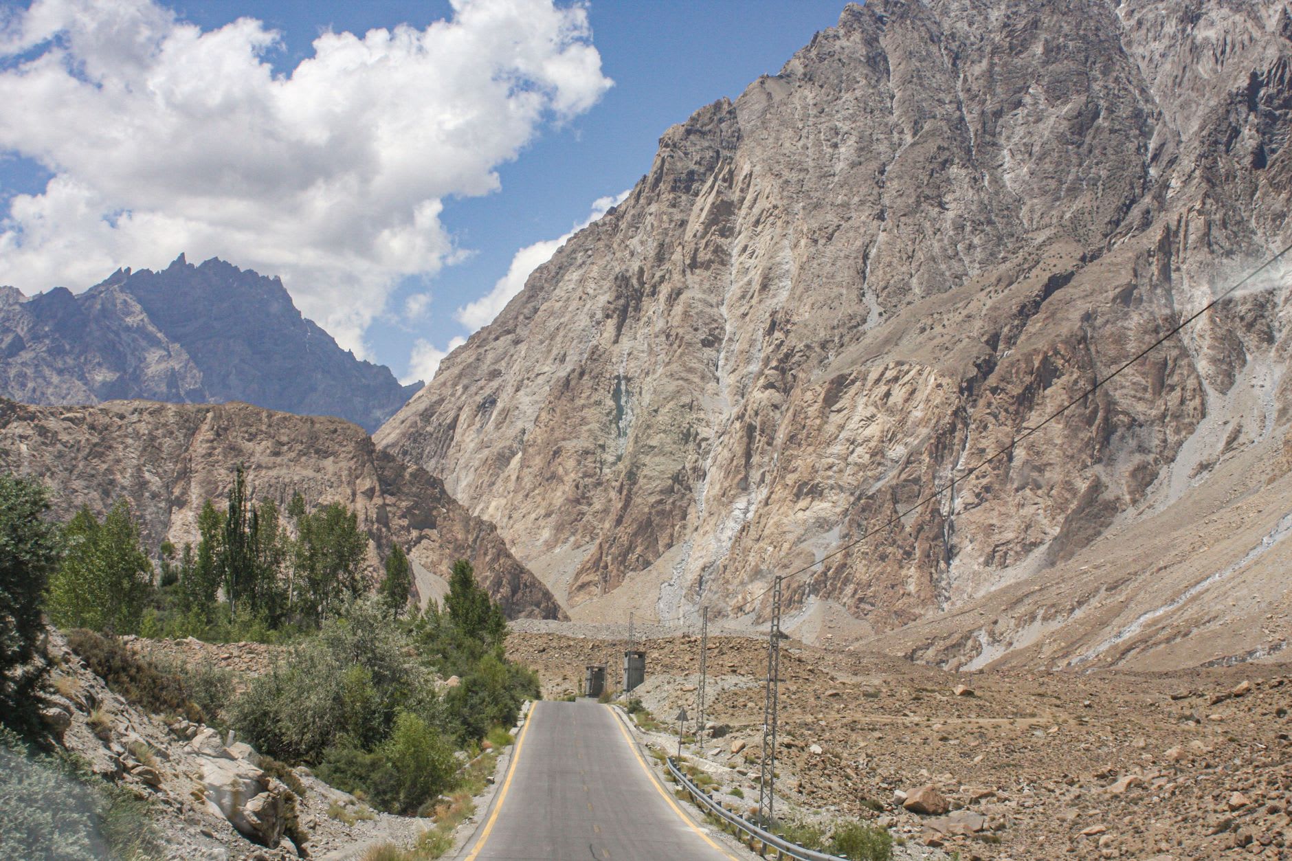 Attabad Lake from the highway: electric-blue water filling a mountain gorge, the old KKH visible under the surface in the shallows