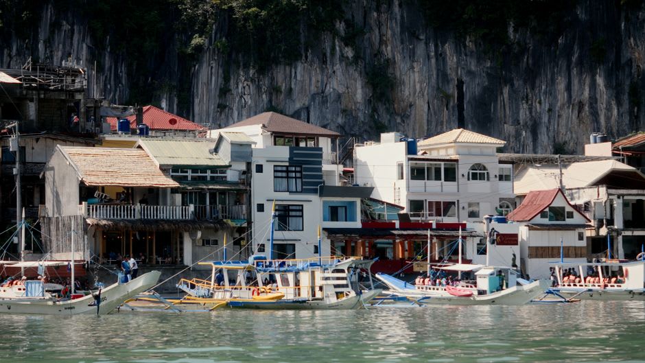 Fishing boats moored in Culion's harbor beneath the old church and fort