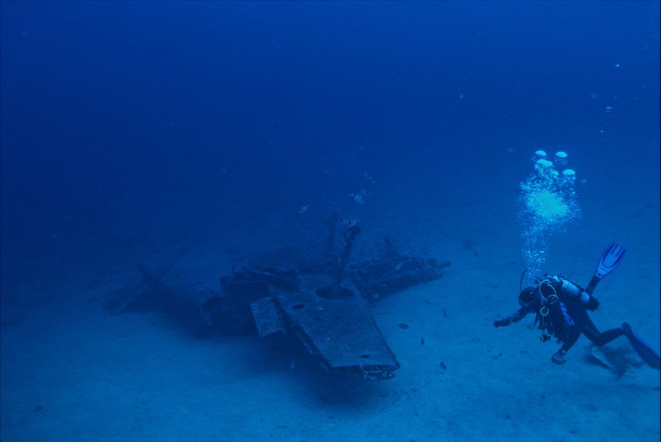 Un avión de combate hundido de la Segunda Guerra Mundial reposando en un lecho marino arenoso cerca de Kavieng, coral empezando a colonizar el fuselaje en aguas azules cristalinas