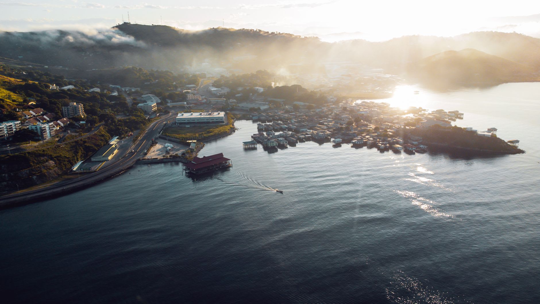 The Koki fish market at dawn, its concrete stalls covered in reef fish and crab, vendors in rubber boots and bright shirts haggling in Tok Pisin