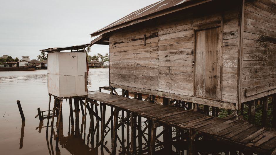 An elevated wooden house on stilts in the flood-prone riverside district of Pilar, a small boat tied beneath the raised porch