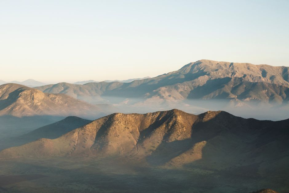 La vista de un senderista desde la cumbre del Cerro Tres Kandú mirando sobre las crestas boscosas de la sierra de Ybytyruzú desvaneciéndose en neblina azul