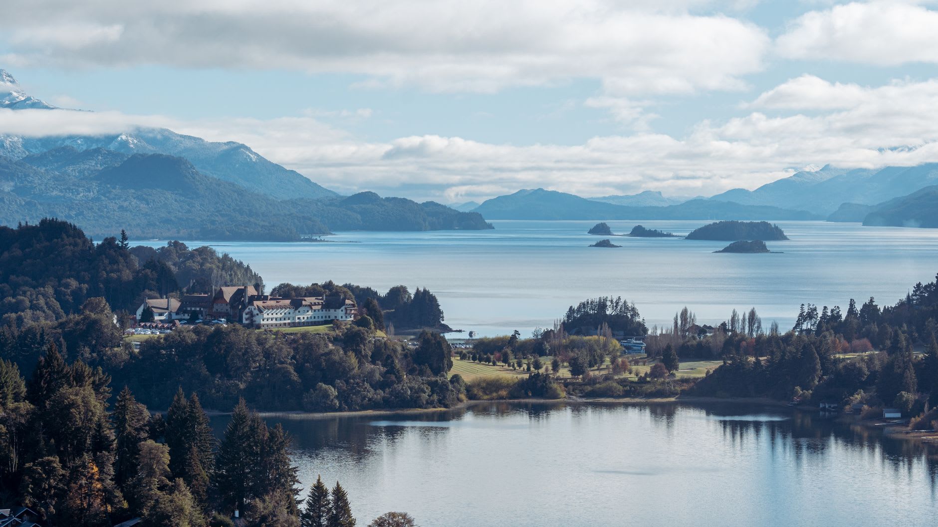 Lago Nahuel Huapi seen from the slopes above Bariloche, islands and snow-capped peaks reflected in the deep blue-green water