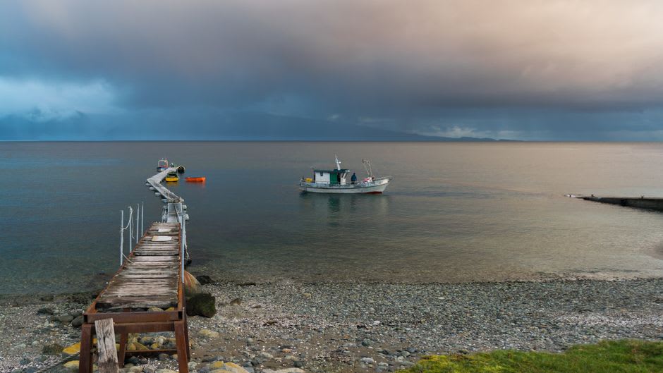 Wooden dock and launch boat departing for Termas de Puyuhuapi across the fjord