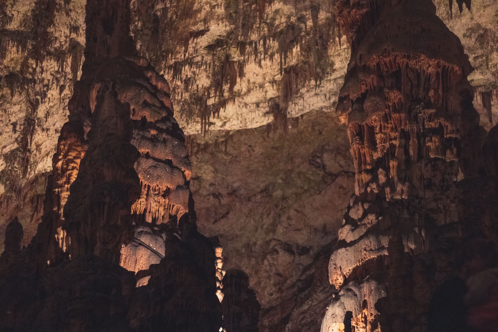 Stalactites and stalagmites in the Diros Caves forming cathedral-like chambers above the dark underground lake