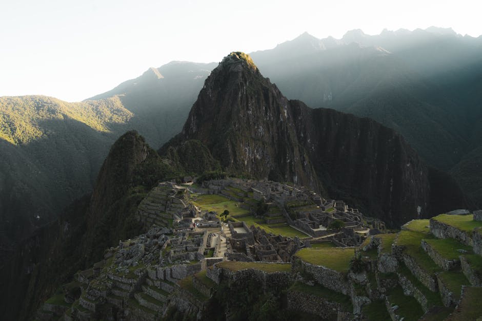 Machu Picchu ruins emerging through morning mist with mountain peaks behind