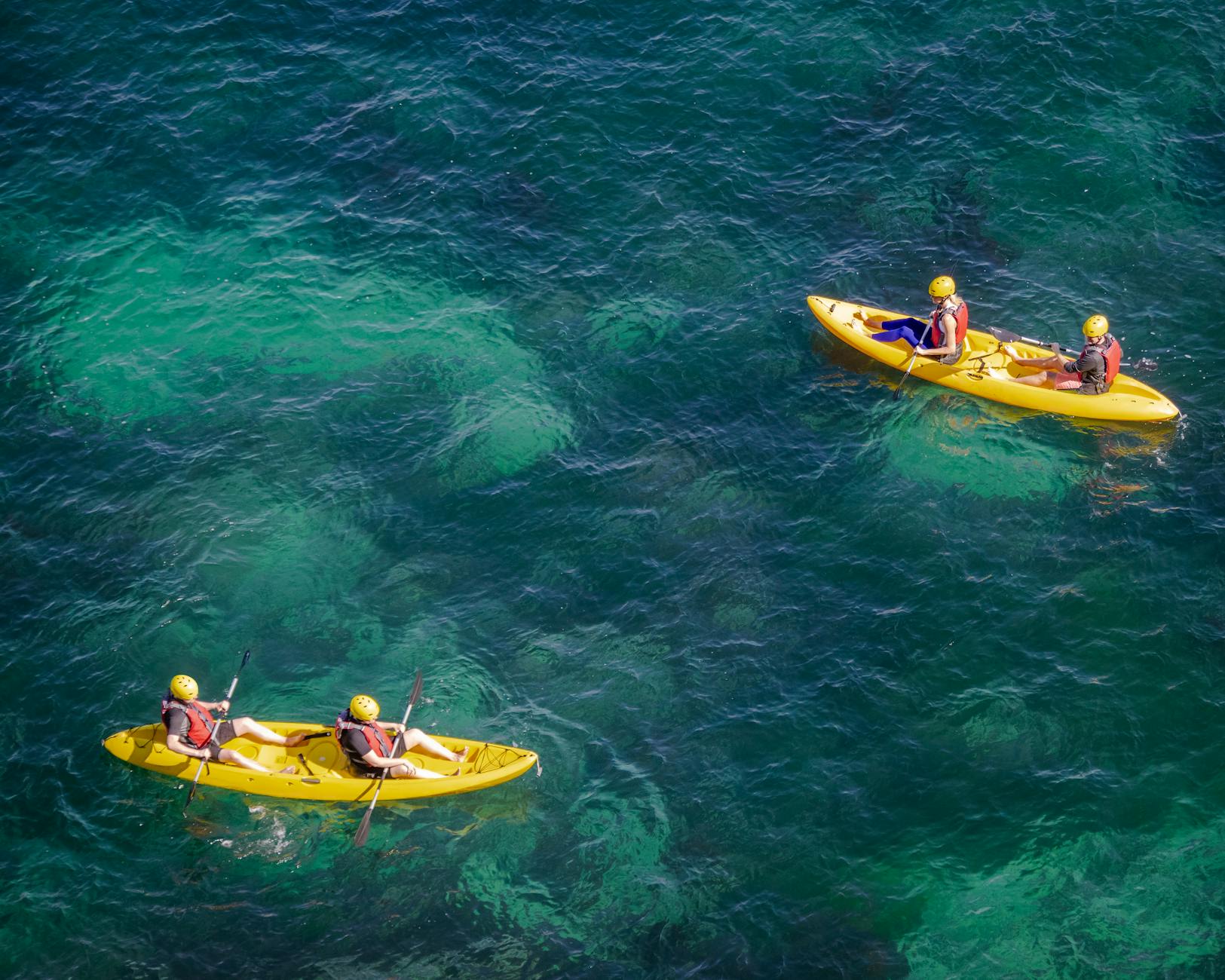 Kayaking through crystal-clear water between towering limestone cliffs