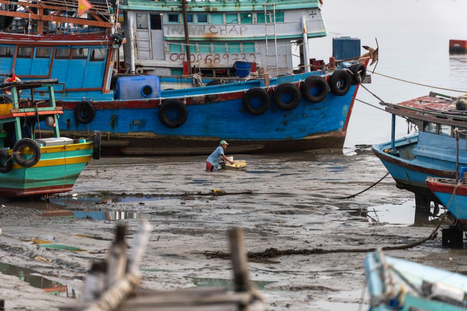 Wooden fishing boats resting on the muddy banks of the Cửa Cạn River at low tide