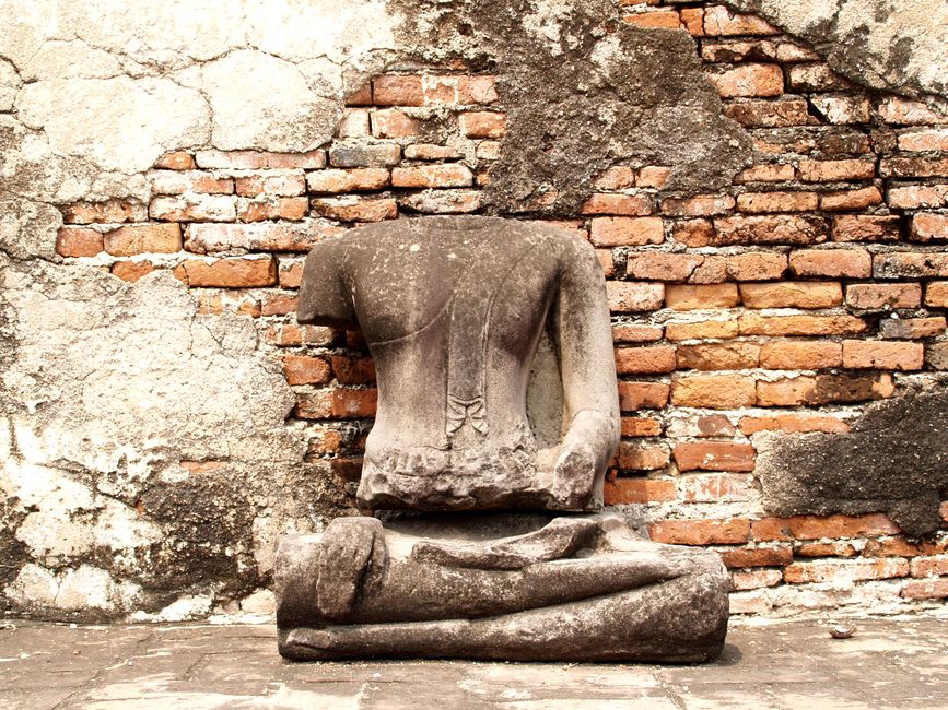 The headless seated Buddha of Wat Piawat surrounded by broken temple columns