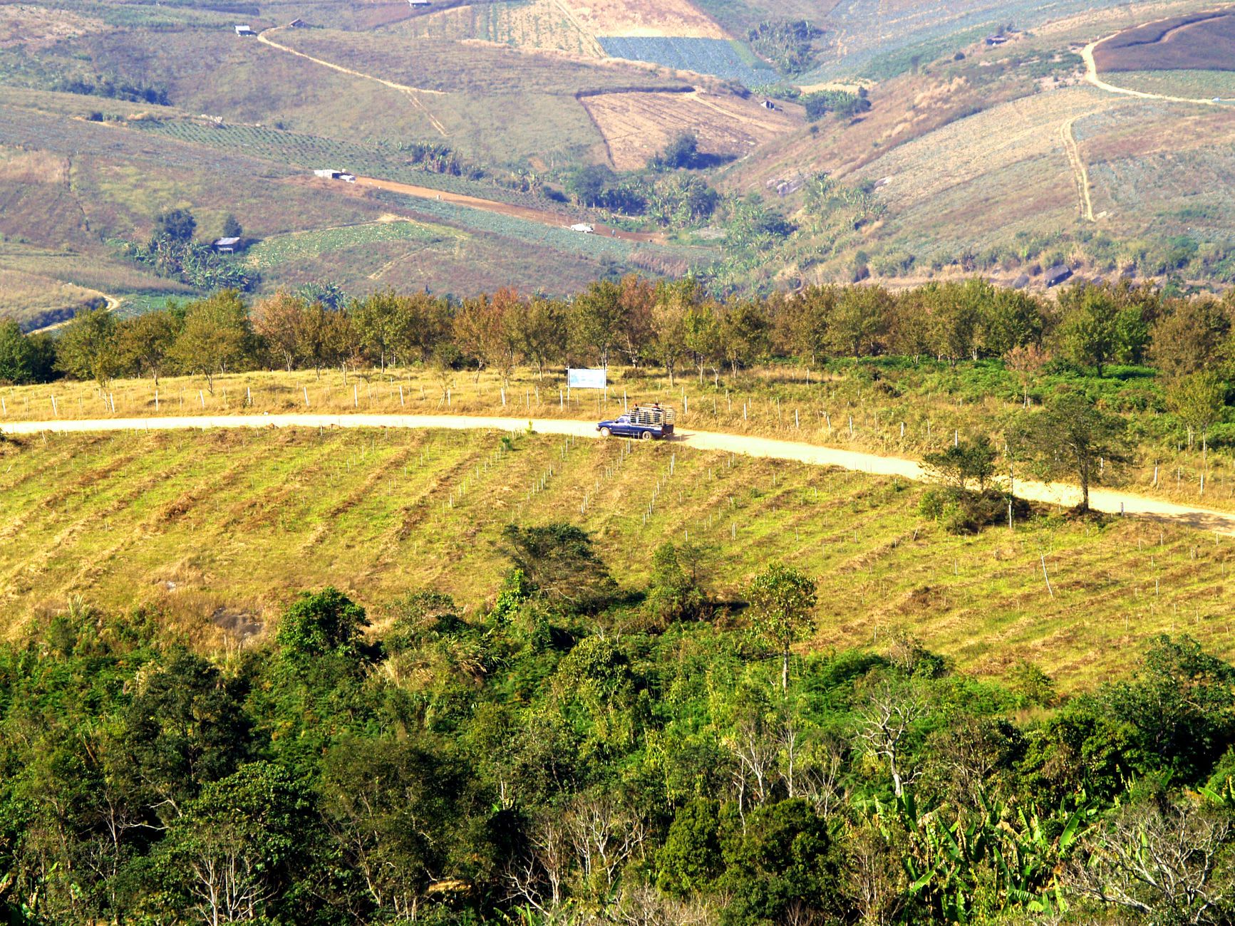 The road approaching Muang Khoun, dropping through river valley farmland from the plateau above
