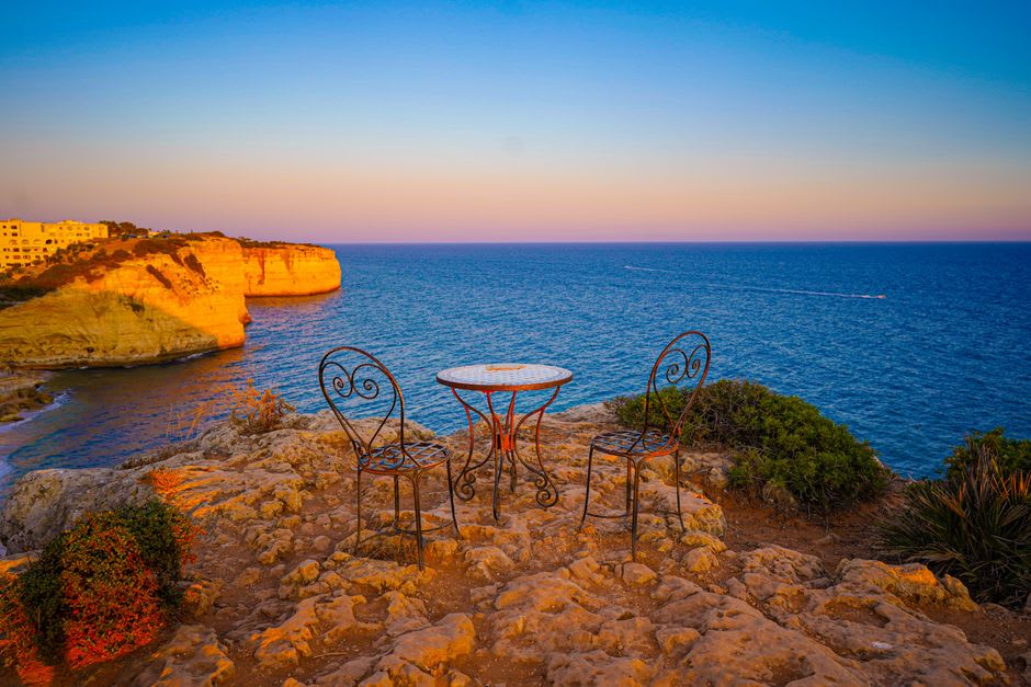 Sunset view from a clifftop miradouro above Albufeira's old town, orange cliffs and coves stretching along the coast