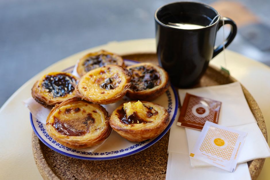 A plate of golden conventual pastries and a glass of coffee on a marble café table in Alcobaça