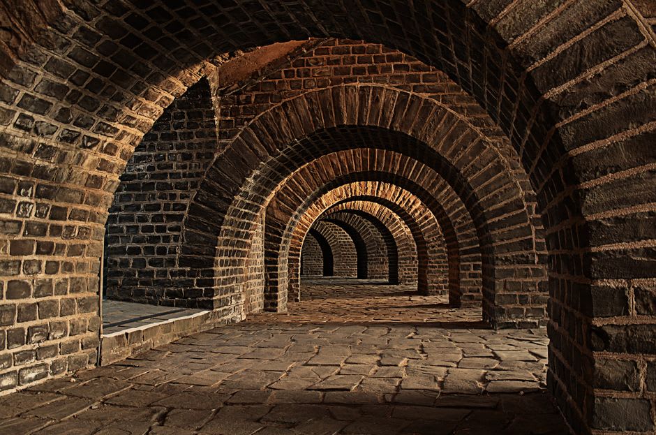Vaulted stone tunnel casemate beneath Almeida fortress, dimly lit and cool