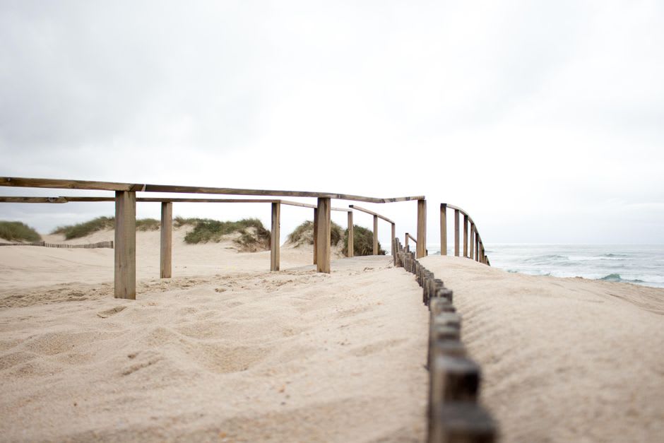 Open wooden carriages of the Transpraia train running along the dunes at Costa da Caparica